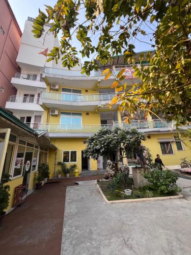 een geel en wit gebouw met een boom bij Vedic Hatha Vinyasa Yoga Ashram in Narendranagar