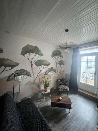 een woonkamer met een muurschildering van bomen op de muur bij Charmant logement avec 2 véranda in Le Vivier-sur-Mer
