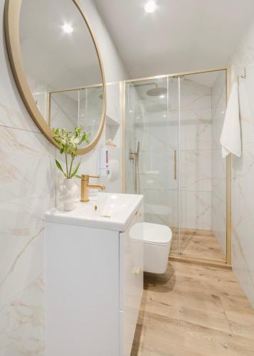 a white bathroom with a sink and a mirror at Apartamenty Mieszka I in Łódź