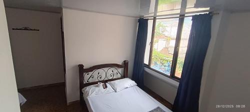 ein kleines Schlafzimmer mit einem Bett und einem Fenster in der Unterkunft Hotel Suite Americano in Pereira