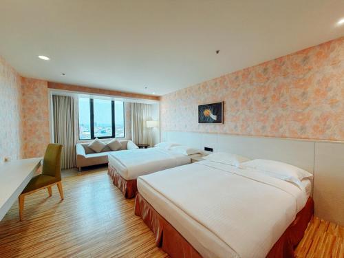 a hotel room with two beds and a couch at Wemeet Hotel in Pingtung City