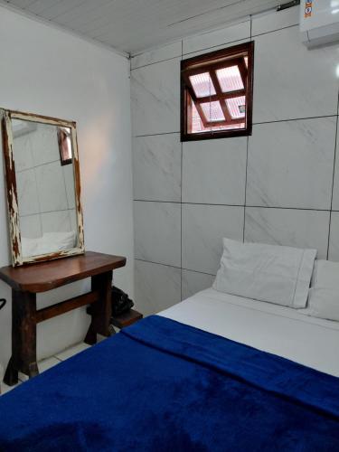 een slaapkamer met een bed, een spiegel en een tafel bij Hostel Aki in Itacaré