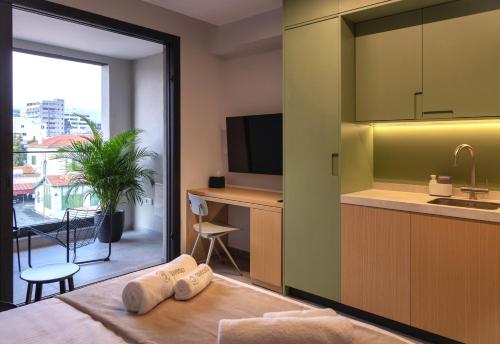 a hotel room with a kitchen and a bed with towels at Aweso Limassol in Limassol