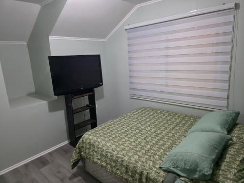 a bedroom with a bed and a flat screen tv at Villa Parque Cordillera 1 in Chillán