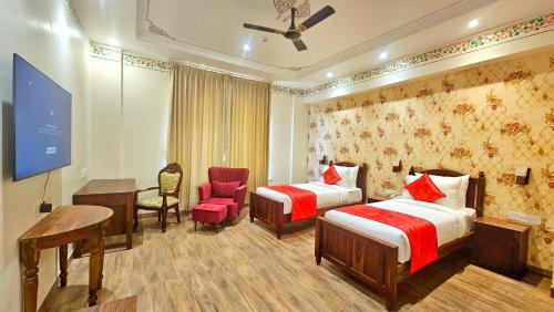 a hotel room with two beds and a desk at Hotel Ranavilas Palace in Jaipur