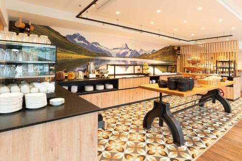 a restaurant kitchen with a mural of mountains on the wall at Basic Rooms Jungfrau Lodge in Grindelwald