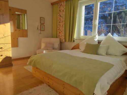 een slaapkamer met een bed, een stoel en een raam bij Ferienwohnung Kerschbaumer in Rangersdorf