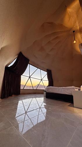 a bedroom with a bed and a large window at Tariq Camp Wadi Rum in Wadi Rum