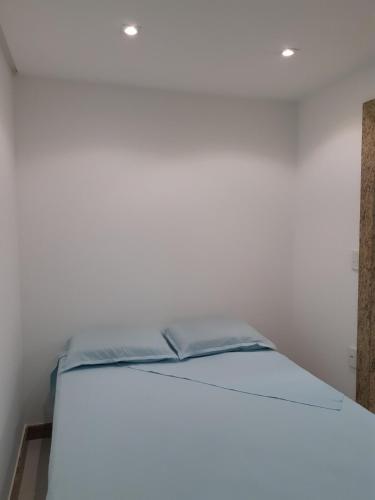 a bed in a room with a white wall at Kitnet acolhedora in Caxias do Sul