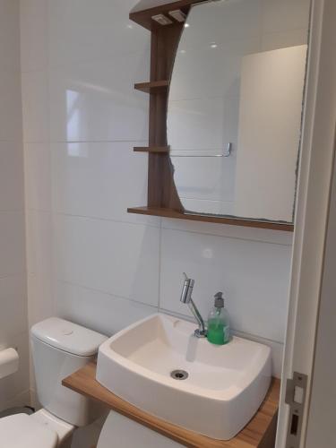 a bathroom with a sink and a mirror and a toilet at Kitnet acolhedora in Caxias do Sul