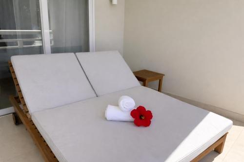 een wit bed met een rode bloem erop bij Cocoon in Anse a La Mouche