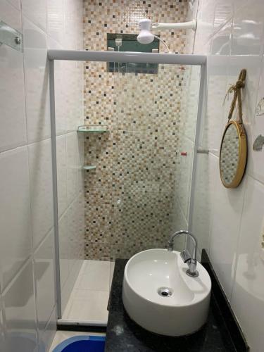a white bathroom with a sink and a shower at Mar & Mar Suites in Arraial do Cabo