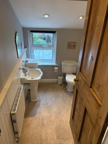 a bathroom with a sink and a toilet and a window at 2 Bed Terrace Cottage with Cathedral Views in Salisbury