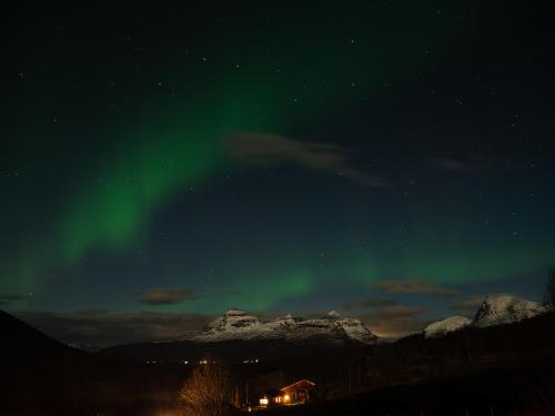 een noorderlicht boven een berg bij Room in Cozy Cottage 