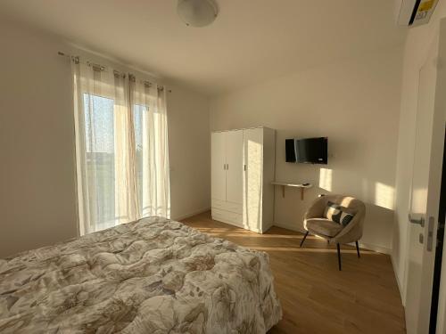 une chambre avec un lit, une chaise et une télévision dans l'établissement Home far from home, à Castelnuovo del Garda