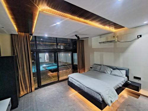 a bedroom with a bed and a large window at Luxe poolside farmhouse -J House in Hyderabad