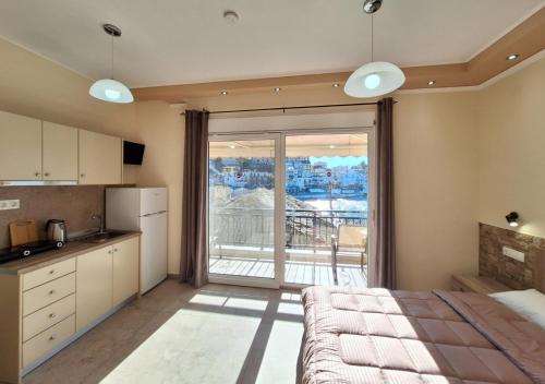 a room with a bed and a kitchen with a large window at Minos Apartments in Skala Marion