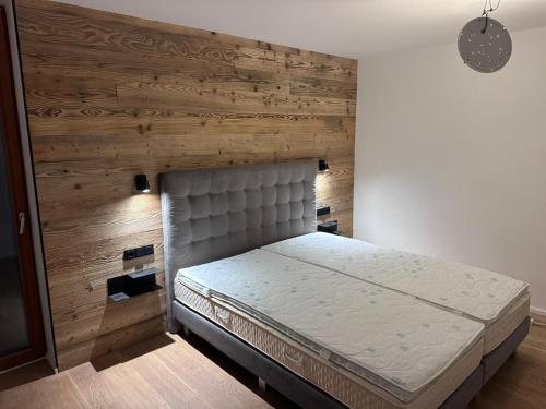 a bed in a room with a wooden wall at Traum in Zell am See mit Badeplatz in Erlberg
