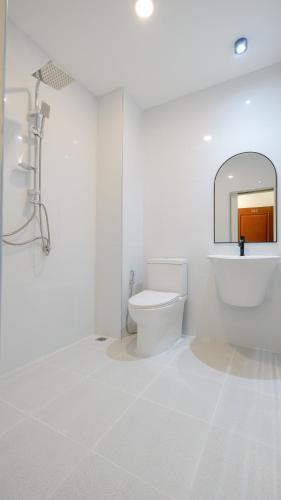 a white bathroom with a toilet and a mirror at Three Monkeys Chaweng Beach in Chaweng