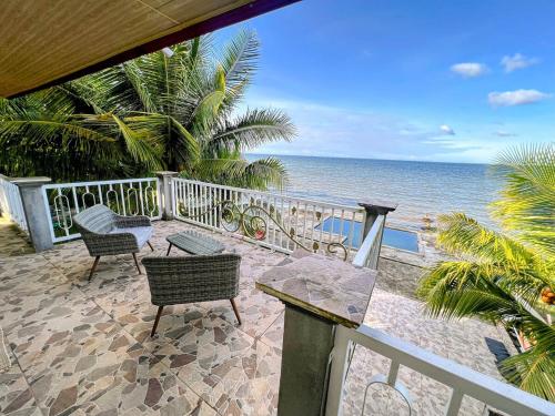 a balcony with chairs and a table and the ocean at Casa Vista al Amatique in Puerto Barrios