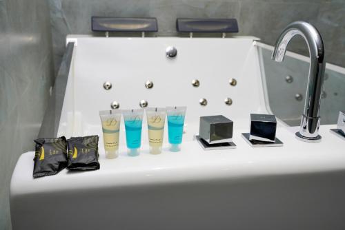 a sink with three glasses and a bathroom sink with a bath tub at نوف بلازا nouf plaza for serviced apartments in Ad Dawādimī