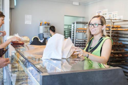 a woman is standing behind a counter in a bakery at Camping Riembau in Platja  d'Aro