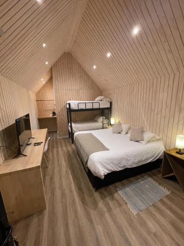 a bedroom with two beds and a television in a room at Hotel Puerto Madera in Pelluhue
