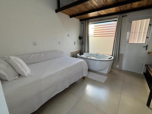 een slaapkamer met een bed en een bad bij Ofurô com hidromassagem aquecida in Guia Lopes da Laguna
