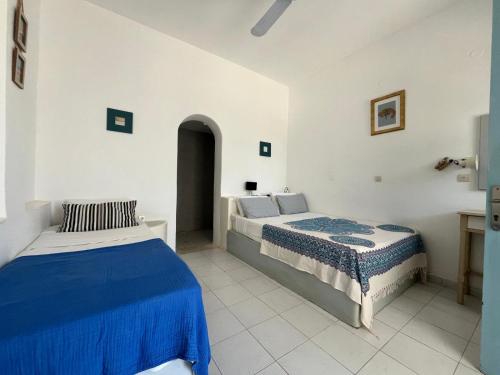 2 bedden in een witte kamer met blauwe lakens bij Villa Campos Yalos beach in Ios Chora