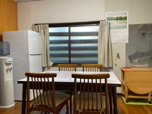 une cuisine avec une table, des chaises et un réfrigérateur dans l'établissement オイソ, à Iiyama