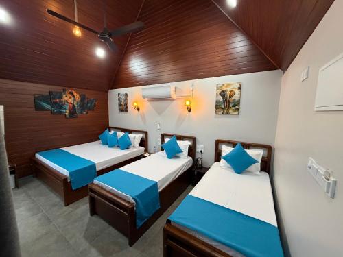 two beds in a room with wooden walls at Batti Lagoon Hotel in Batticaloa