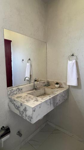 a bathroom with a marble sink and a mirror at Vila Gaheri in São Miguel dos Milagres