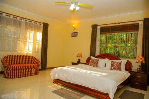 een slaapkamer met een bed, een stoel en een raam bij CALM SUITES KAMPALA in Kampala