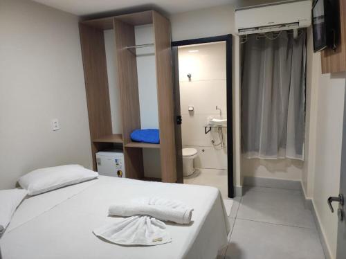 a bedroom with a white bed and a bathroom at Estrela de davi in Goiânia