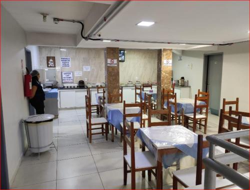 a restaurant with tables and chairs and a person in a kitchen at Estrela de davi in Goiânia