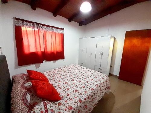 een slaapkamer met een bed met rode kussens erop bij Brisas de las Sierras in Tanti