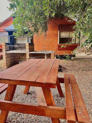 une table de pique-nique en bois devant un bâtiment dans l'établissement Cabañas Vega del Molino, à Linares