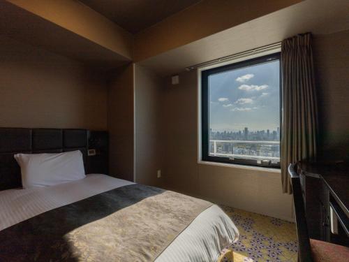 a bedroom with a bed and a large window at APA Hotel Shin Osaka Ekimae Tower in Osaka