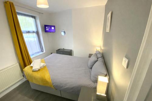a small bedroom with a bed and a window at Emerald Living, 4 bedrooms, sleeps 6, free parking, close to centre and beaches! in Swansea