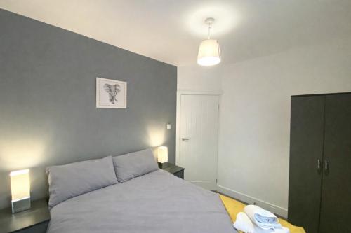 a bedroom with a bed and a blue wall at Emerald Living, 4 bedrooms, sleeps 6, free parking, close to centre and beaches! in Swansea