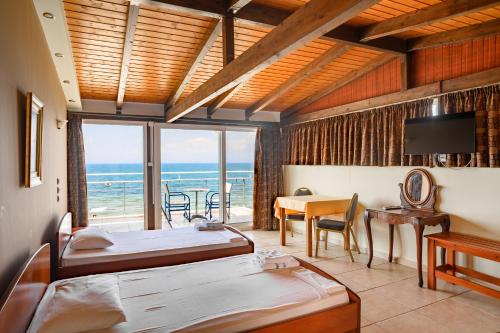 a bedroom with two beds and a table and a balcony at Hotel Dimitra in Tsoukalaíika