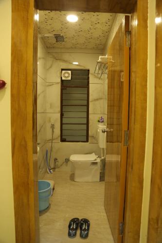 een badkamer met een toilet en twee paar schoenen bij ShivAOM Family Homestay in Ujjain