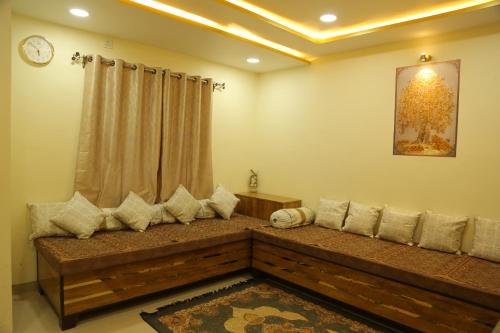een woonkamer met een bank met een klok aan de muur bij ShivAOM Family Homestay in Ujjain