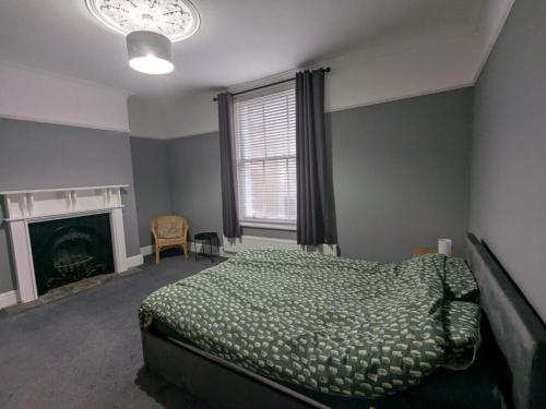ein Schlafzimmer mit einem grünen Bett und einem Kamin in der Unterkunft Seaside 3 bed terraced house in Hastings