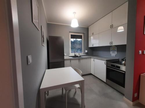 een keuken met witte kasten en een tafel. bij Czapury in Czapury