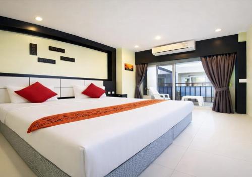 ein Schlafzimmer mit einem großen weißen Bett mit roten Kissen in der Unterkunft The Star House in Patong Beach