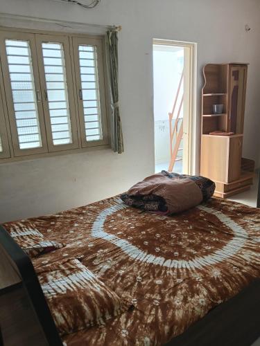 a bedroom with a large bed with a blanket on it at Keshav in Bhuj