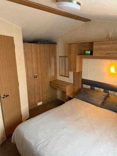 a bedroom with a white bed and wooden cabinets at Casa MALC Caravan in Lossiemouth