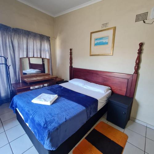 een slaapkamer met een groot bed en een spiegel bij HostHub Guest House in Rustenburg