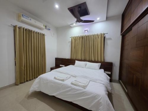a bedroom with a bed and a tv on the wall at Ixe Stays in Mangalore